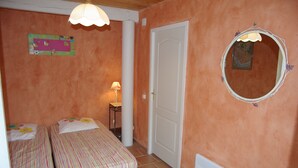 A bedroom with two beds, a door, a lamp, and a mirror on the wall. - House with swimming pool in exceptional surroundings (Ferrières-Poussarou)