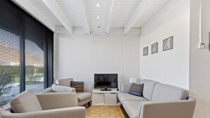 A modern living room with a TV, two sofas, and a herringbone-patterned floor. - 3 bedroom accommodation in Nieuwpoort (Nieuwpoort)