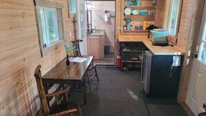 Un accogliente chalet in legno con zona pranzo, angolo cottura e bagno piccolo.