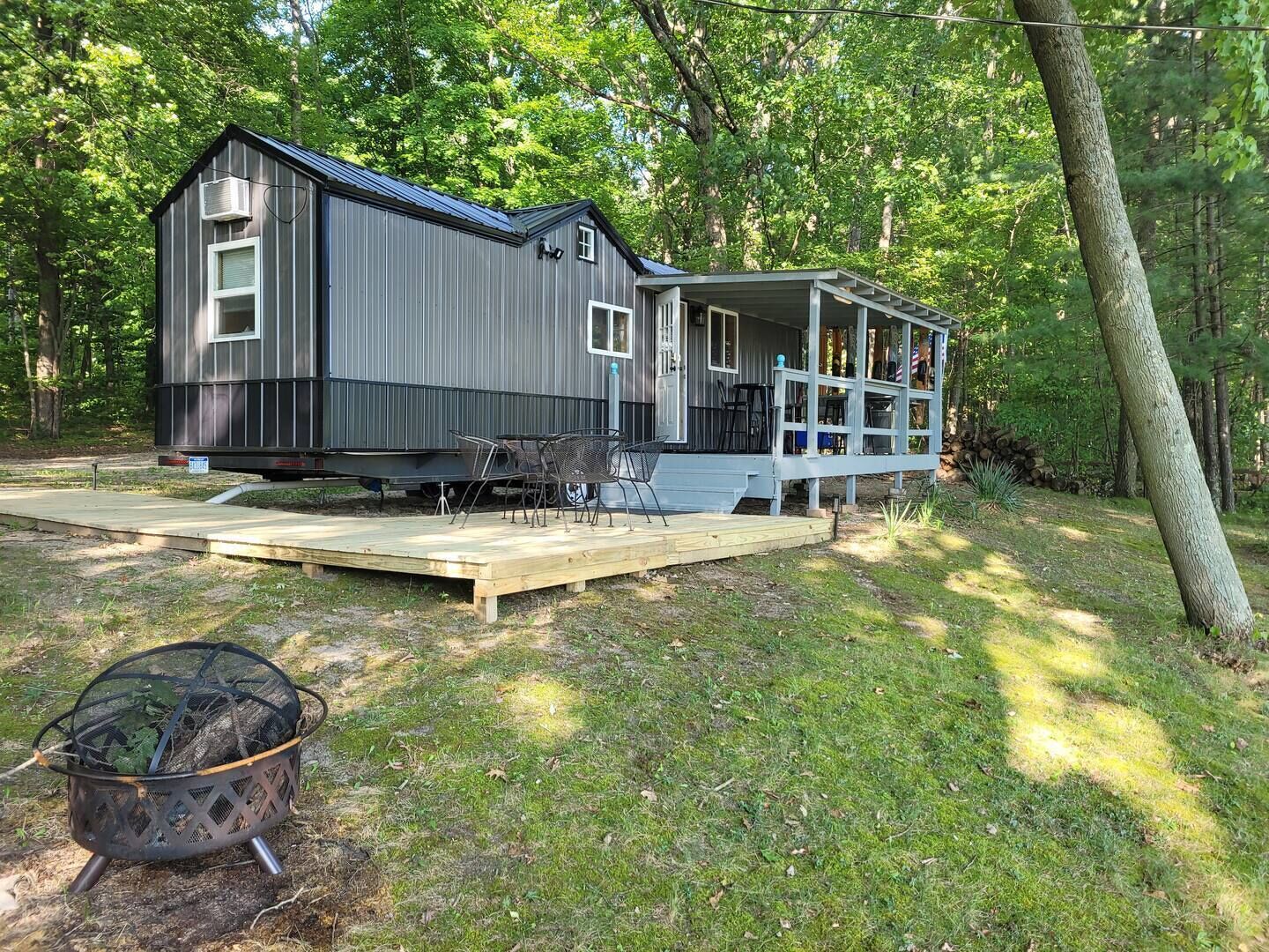 Een chalet met veranda, terras en vuurkuil.