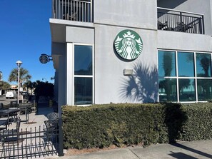 Ein Starbucks mit großem Logo an der Fassade, Außenbereich und einer gepflegten Hecke.