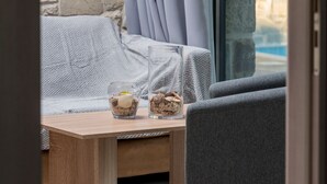 Un rincón acogedor con pared de piedra, un banco acolchado y una mesa de vidrio con dos recipientes de helado.