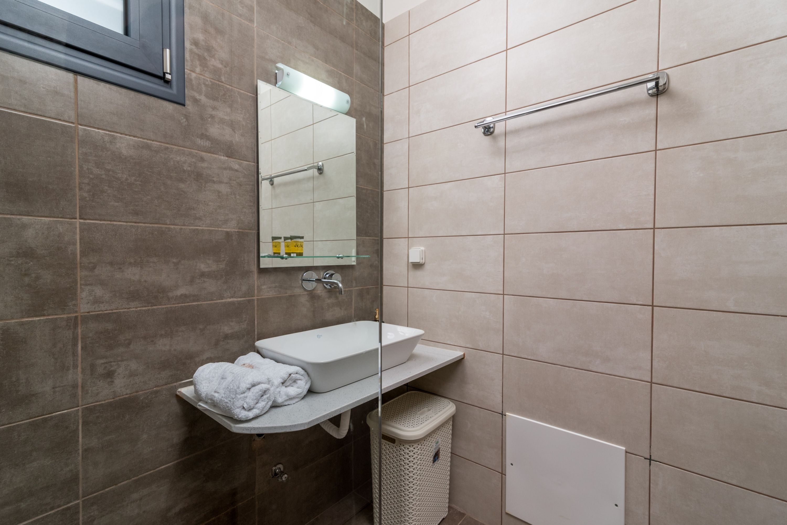 A modern bathroom with a white sink, a mirror, and a towel rack.