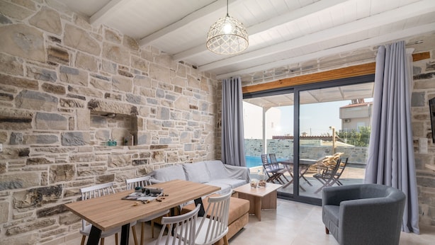 Amplia sala de estar con pared de piedra, muebles de madera y un balcón con vistas.