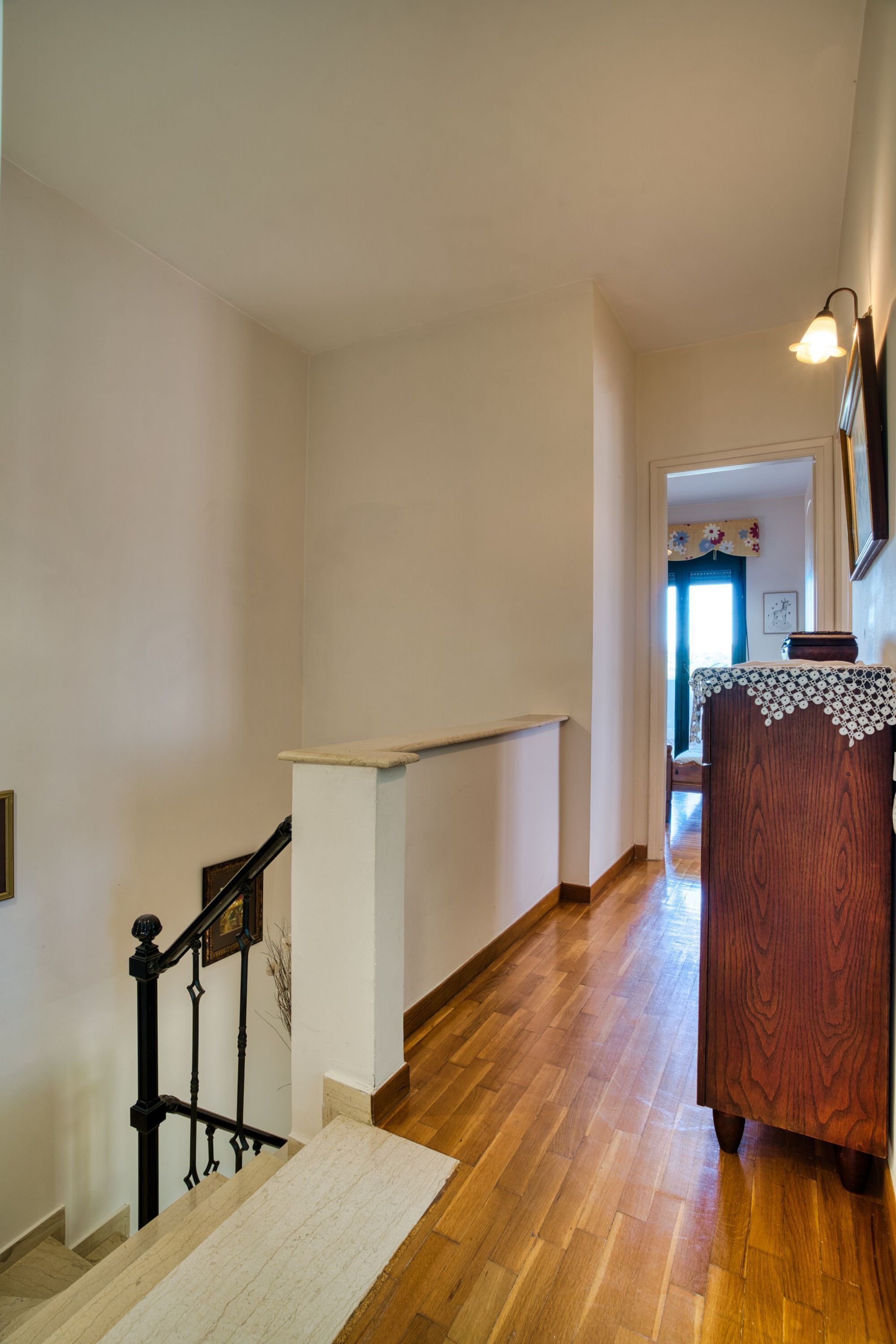 A wooden staircase with a white handrail leading to a landing.