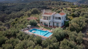 A modern two-story house with a swimming pool, surrounded by dense greenery and hills. - Villa Panorama - With 60m Private Pool (Rethymno)