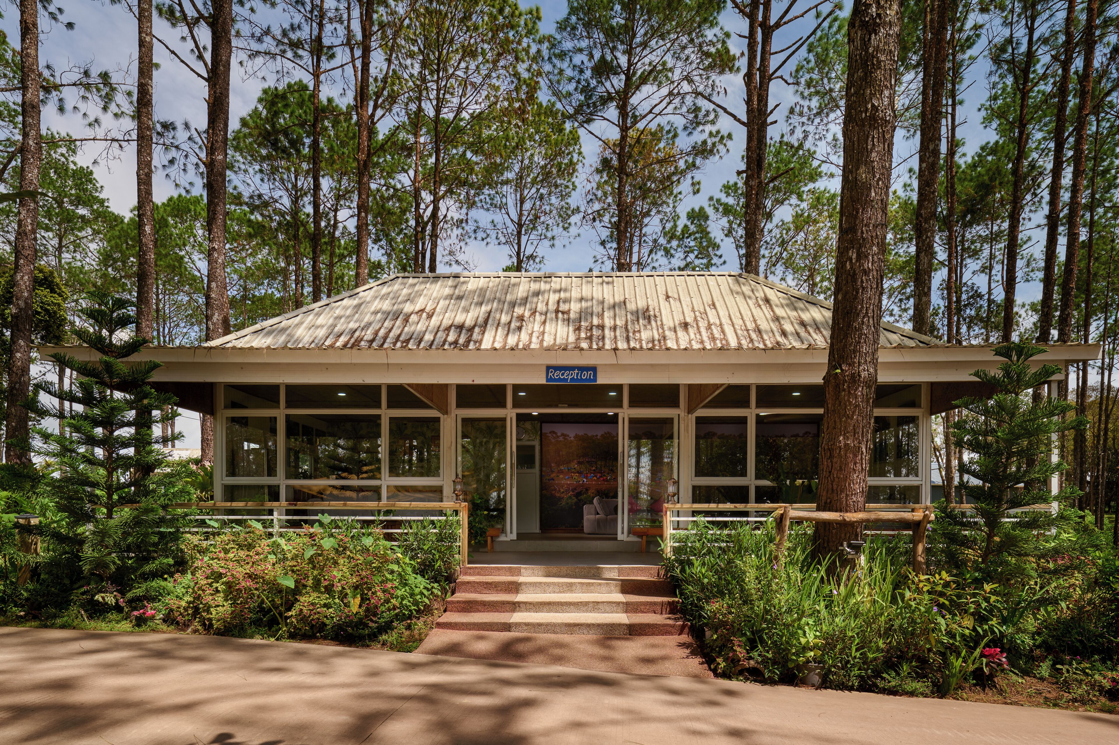 A reception building with a metal roof, surrounded by trees and plants.