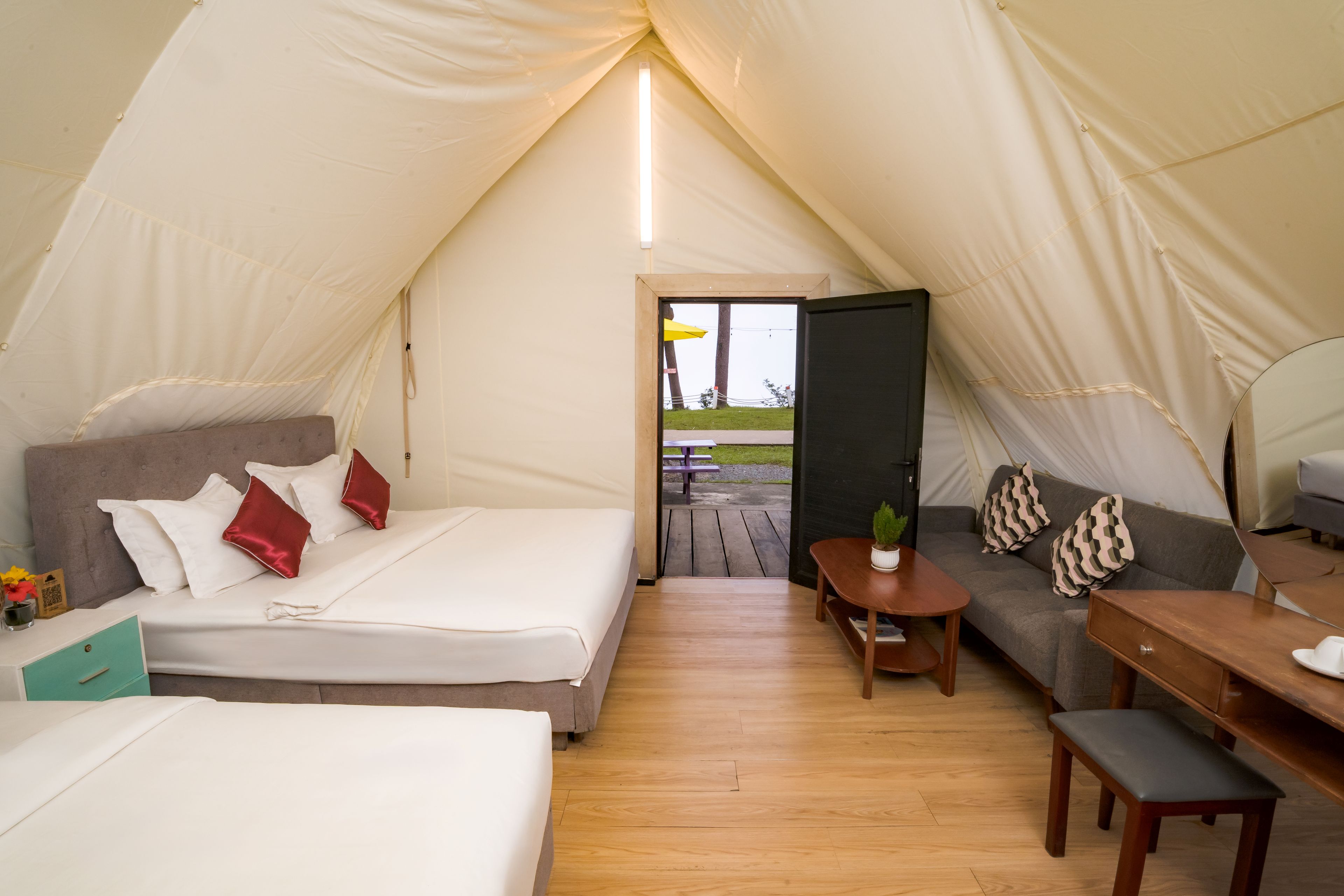 A tented accommodation with a bed, sofa, and table.