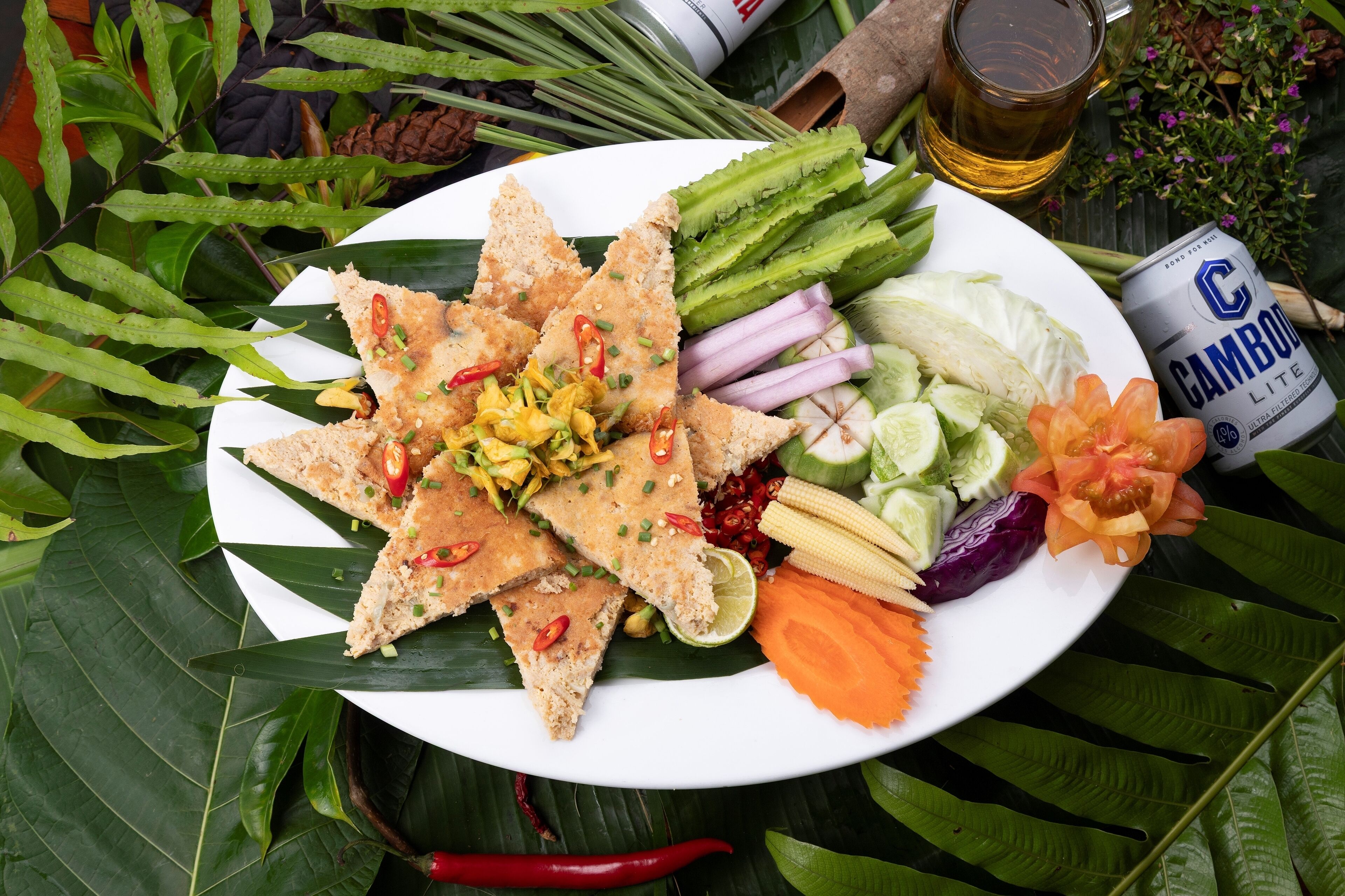 Une assiette remplie de divers légumes et une canette de bière.