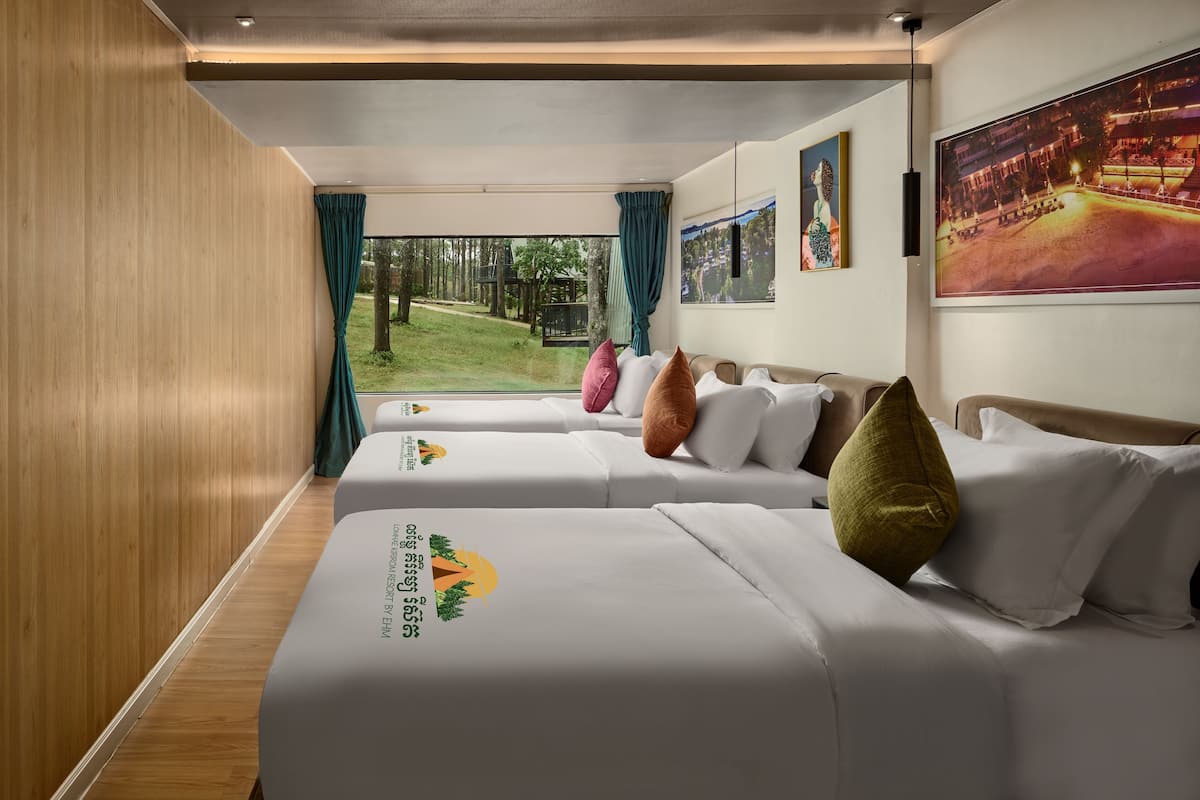 Habitación de hotel con dos camas, un ventanal con cortinas y obras de arte en las paredes.