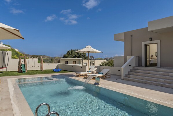 A swimming pool with a clear view of the surrounding area, including a building with steps leading to a door and a view of the landscape.
