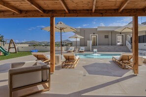 A poolside area with lounge chairs, umbrellas, and a children's playset. - Elysian Villa 2 - With Private Pool (Mylopotamos)