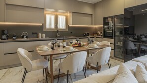A modern kitchen with a dining area, featuring a marble floor, contemporary furniture, and built-in appliances. - Elysian Villa 2 - With Private Pool (Mylopotamos)