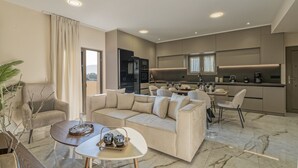 Un salon moderne avec un canapé, une table basse et un coin repas, la cuisine étant visible au fond.