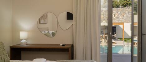 A hotel room with a bed, a bedside table with a lamp, a mirror, and a view of an outdoor swimming pool.