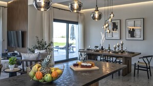 A modern kitchen with a fruit bowl, dining table, and bar area. - Villa Lux Solis - With 2 Pools (Mylopotamos)