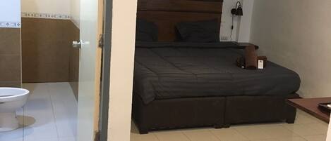 A bedroom with a bed, a bedside table, a lamp, and a nightstand.