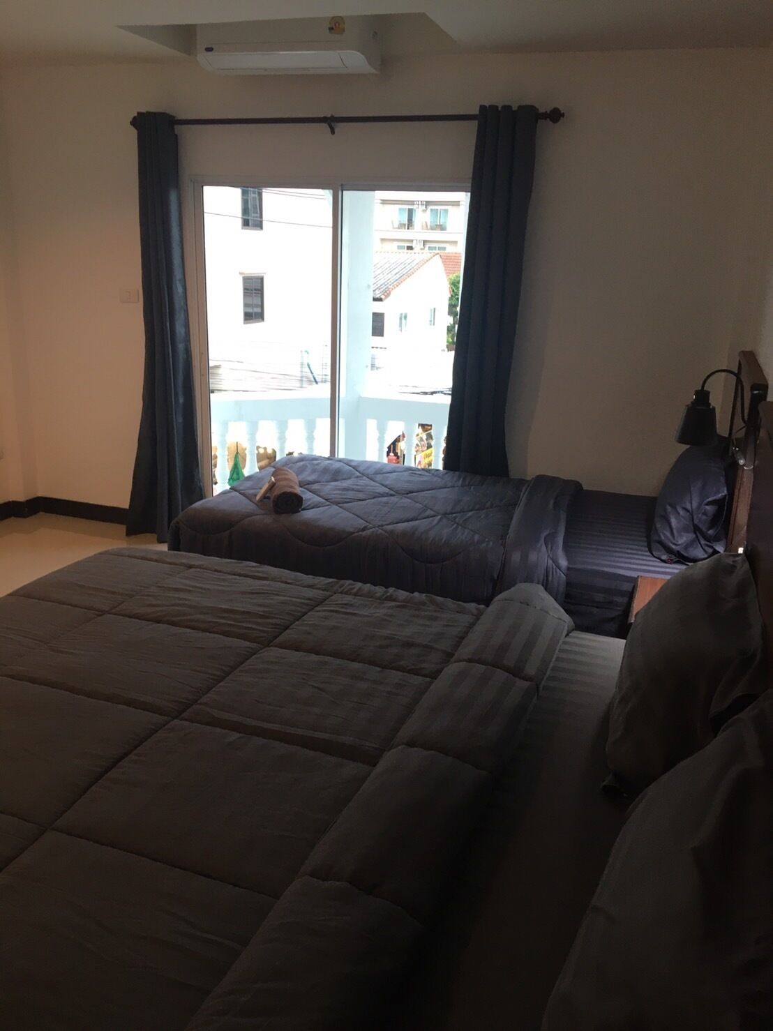 A bedroom with a large bed, a smaller bed, and a window with curtains.