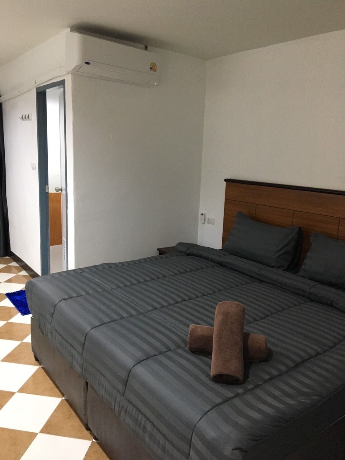 A bedroom with a large bed, a wooden headboard, and a blue and white checkered floor.