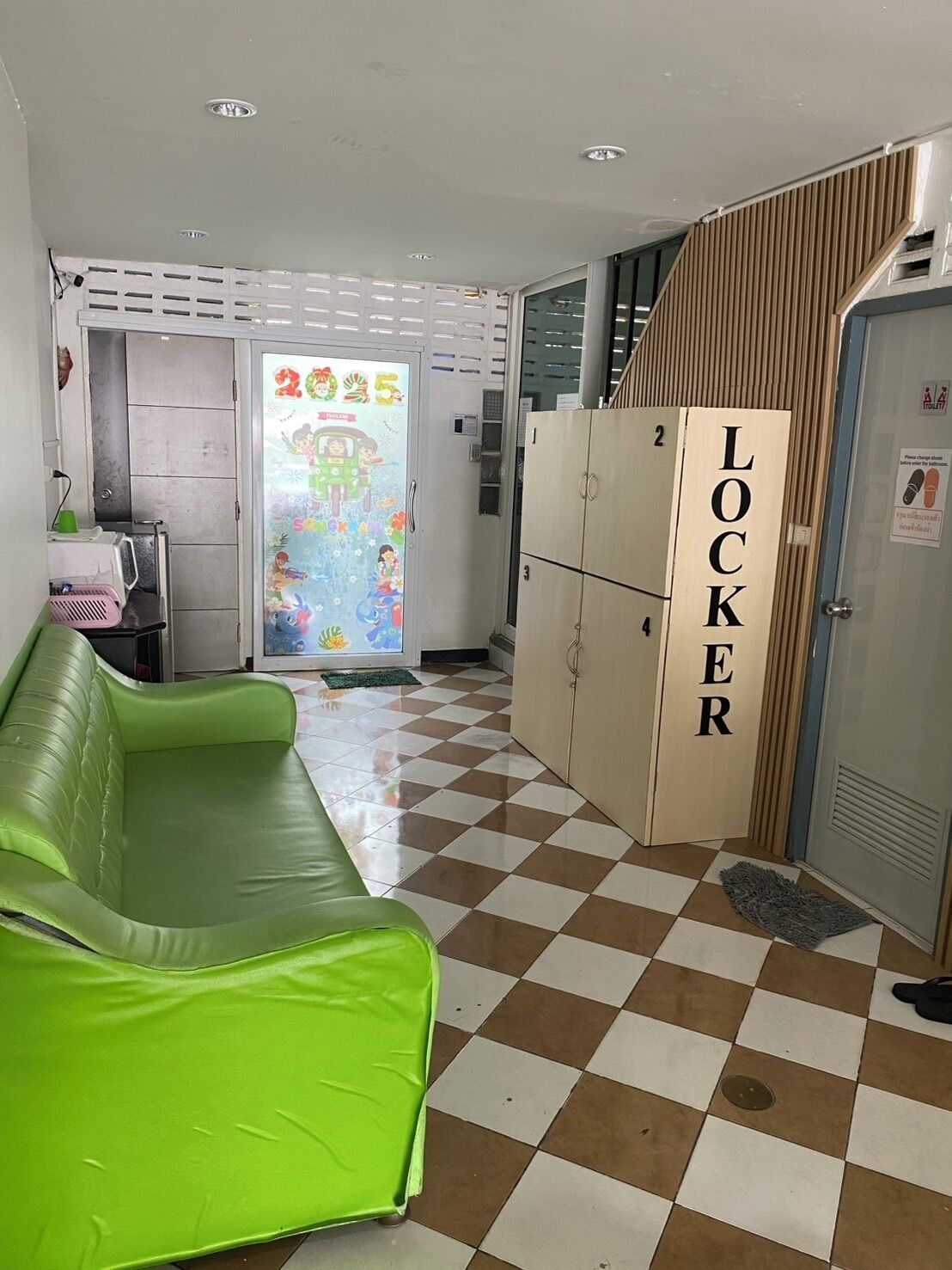 A room with a green sofa, a locker, and a checkered floor.
