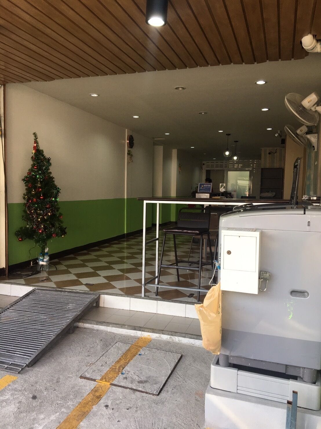 Piso quadriculado, árvore de Natal, máquina de vendas automática e balcão com uma cadeira.