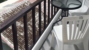 A balcony with a glass table and white chairs, overlooking a residential area with houses and a swimming pool. - Smart Place Pattaya (Pattaya)