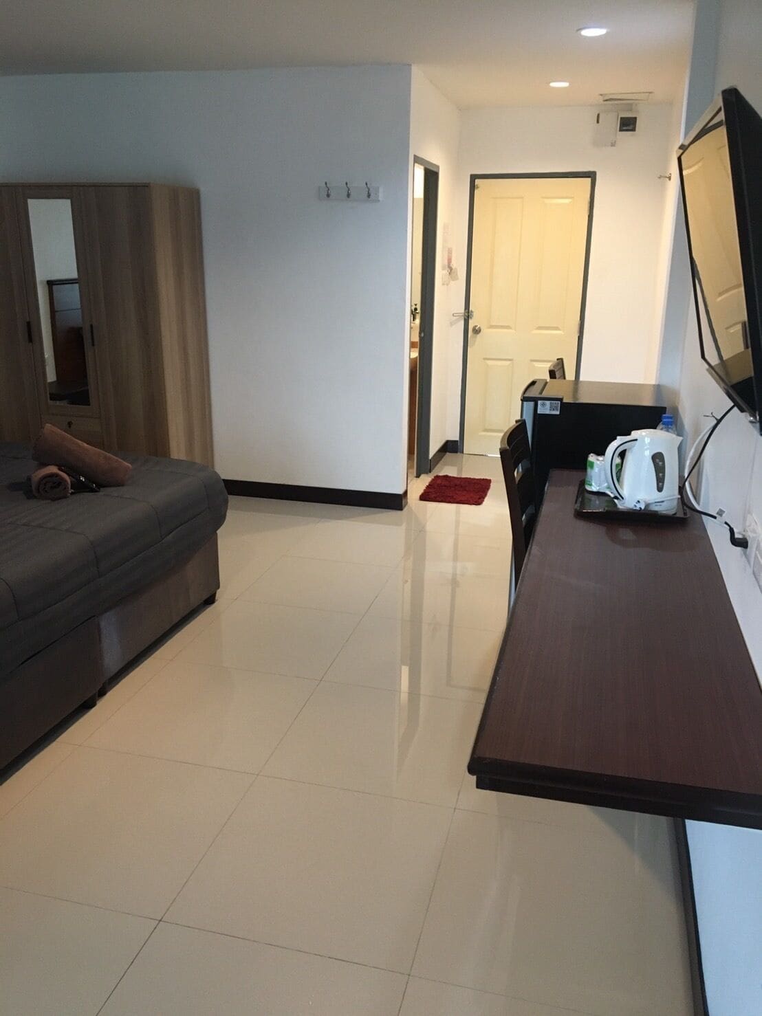 A modern hotel room with a bed, a desk, a chair, a coffee maker, and a TV.