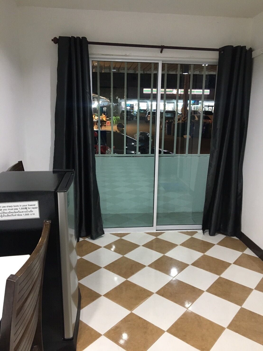 Una habitación con suelo a cuadros, una puerta corrediza de vidrio y una mesa con un letrero.