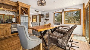 Eine moderne Küche mit einem Holztisch, grau gepolsterten Stühlen und Korbstühlen.