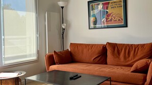 Et værelse med en sofa, et bord, en lampe og et billede på væggen.