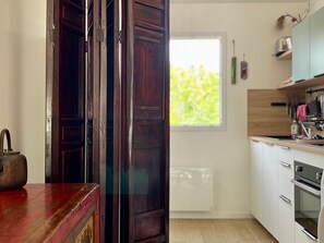 A kitchen with wooden cabinets, a red countertop, and a window with a view of greenery. - New apartment with terrace and parking in Groix (Groix)