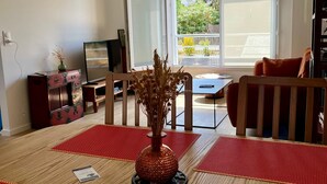 En stue med et fjernsyn, et bord med en vase og en sofa.