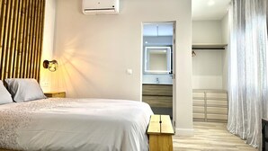 A modern bedroom with a bed, a ceiling fan, an air conditioning unit, a bedside lamp, and a wooden headboard. - Modern, functional studio 15 min from center with Wi-Fi and air conditioning (Málaga)