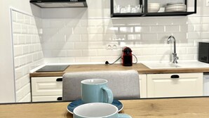 A modern kitchen with white tiles, a black range hood, a wooden countertop, and a shelf with dishes. - Modern, functional studio 15 min from center with Wi-Fi and air conditioning (Málaga)