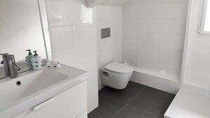 Une salle de bain moderne avec un lavabo blanc, un miroir et des toilettes.