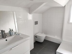A modern bathroom with a white sink, mirror, and toilet.