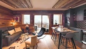 Een gezellige woonkamer met een bank, een eettafel met stoelen en een open haard.