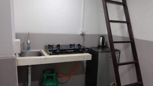 Una cocina compacta con estufa a gas, lavamanos y un refrigerador pequeño.