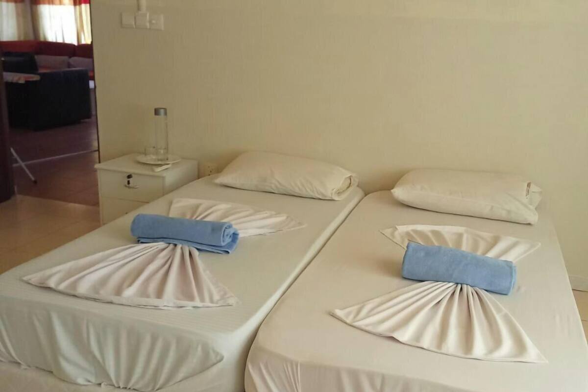 Ett hotellrum med två sängar, där varje säng har en prydligt vikt vit filt och en blå handduk.