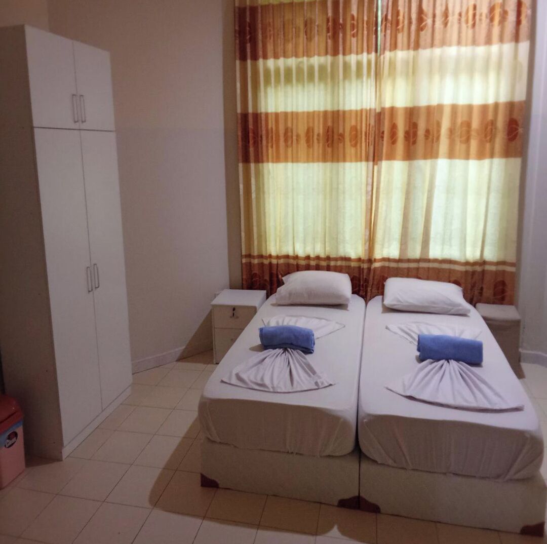 A twin room with two beds, a wardrobe, and a window with curtains.