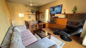 Una sala de estar con un sofá, una mesa de centro y un televisor montado en la pared.