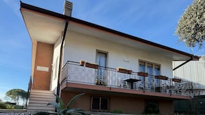 Un edificio de dos pisos con balcón, un letrero que dice “Villa Gianfranca” y un camino de entrada de grava.