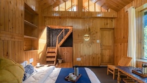 A wooden cabin with a bed, a dining table, a chair, a coffee tray, and a staircase. - Jibhi Village (Banjar)