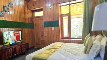 Quarto de madeira com uma cama, uma televisão e uma janela com cortinas.