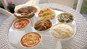 A table with various dishes, including rice, and a basket of flatbread. - Jibhi Village (Banjar)