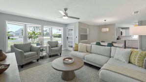 A modern living room with a white sofa, two armchairs, a coffee table, and a dining area with a table and chairs. - New Listing Discount! Coconut Cove - Heated, Saltwater Pool/Spa - fully renovated! (Naples)