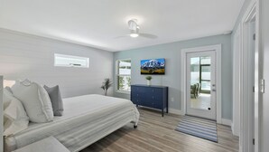 A bedroom with a bed, a dresser, a painting, and a door leading to a balcony. - New Listing Discount! Coconut Cove - Heated, Saltwater Pool/Spa - fully renovated! (Naples)
