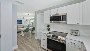 A modern kitchen with white cabinets, a stainless steel microwave, a gas stove, and a toaster. - New Listing Discount! Coconut Cove - Heated, Saltwater Pool/Spa - fully renovated! (Naples)