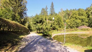A gravel path leading to a pond surrounded by trees and a stone wall. - Lakefront Family Retreat (Harzgerode)