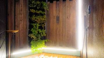 Una terraza de madera con ducha integrada y un pequeño espacio para sentarse.